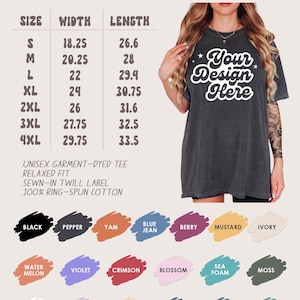 May include: Dark grey unisex t-shirt with the text "Your Design Here". The image shows a size chart with measurements in inches (converted to cm) and a color palette including black, berry, and denim. The shirt is a unisex garment-dyed tee, relaxed fit, sewn-in twill label, and made of 100% ring-spun cotton.