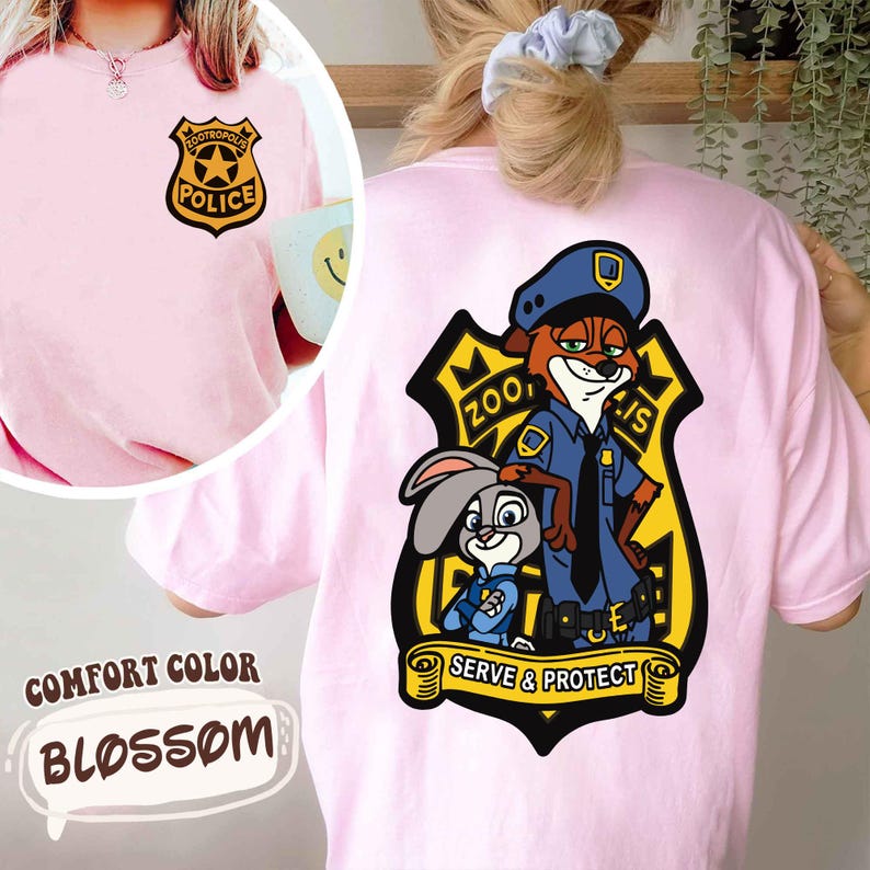 May include: Pale pink Comfort Color Blossom t-shirt with a Zootopia police badge on the front and a larger graphic on the back featuring Nick Wilde and Judy Hopps. The graphic includes the text "Zootopia Police" and "Serve & Protect".