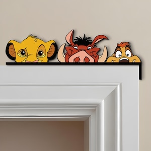 May include: A decorative door frame topper featuring Simba, Pumbaa, and Timon from The Lion King. The characters are in vibrant colors, with a black border. The topper is designed to sit above a door frame, adding a touch of Disney charm.