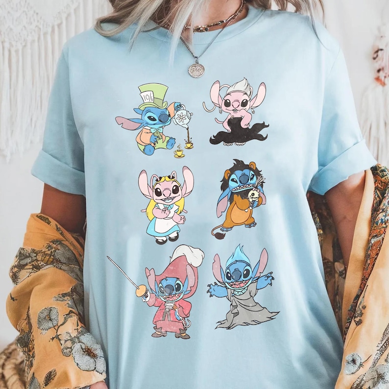 Puede incluir: Una camiseta de manga corta de color azul claro con un estampado gr&aacute;fico de seis personajes de dibujos animados disfrazados. Los personajes aparecen con trajes coloridos, incluyendo un tema de fiesta de t&eacute;, un disfraz de pirata y una t&uacute;nica oscura.