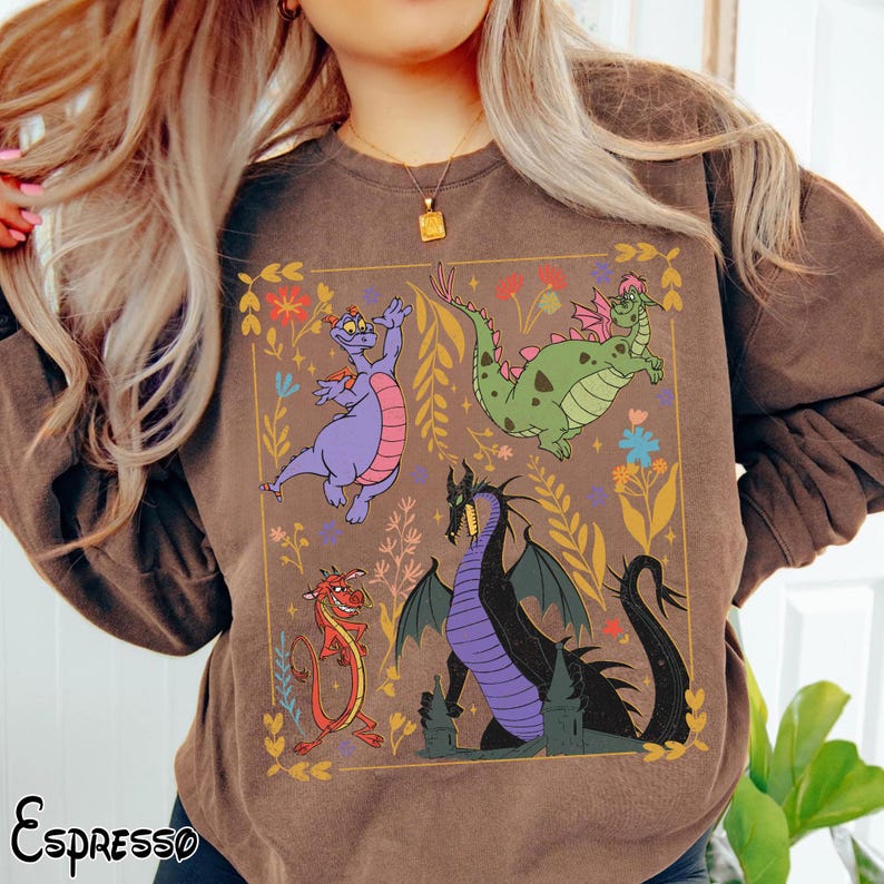 May include: Brown sweatshirt featuring a colorful dragon graphic within a gold-colored frame. The design includes a purple dragon, a green dragon, a red dragon, and a black dragon. The word "Espresso" is printed in the bottom left corner.