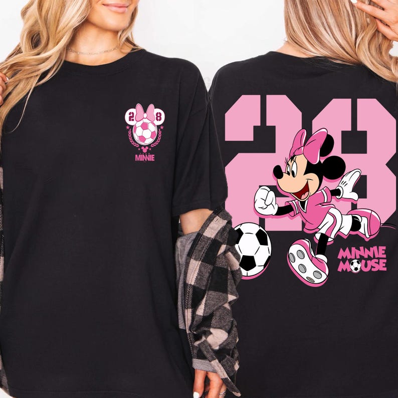May include: Black t-shirt with a pink Minnie Mouse soccer design. The front features a soccer ball graphic with the number 28 and the word "Minnie". The back shows a large pink number 28 and Minnie Mouse kicking a football.