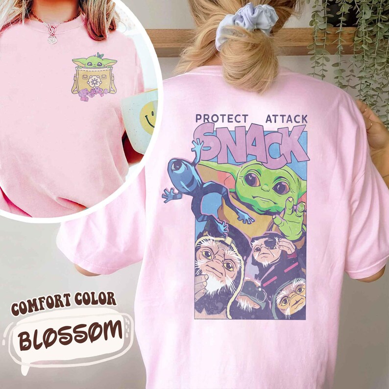 May include: A light pink comfort color t-shirt with a graphic on the front and back. The front graphic features a cartoon character in a box with flowers. The back graphic says "PROTECT ATTACK SNACK" with cartoon characters.