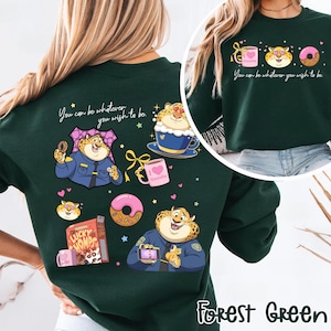 May include: Forest green sweatshirt featuring cartoon cheetah illustrations with donuts, coffee, and cereal. Text reads "You can be whatever you wish to be." The design includes the text "Gazelle" on a mug.