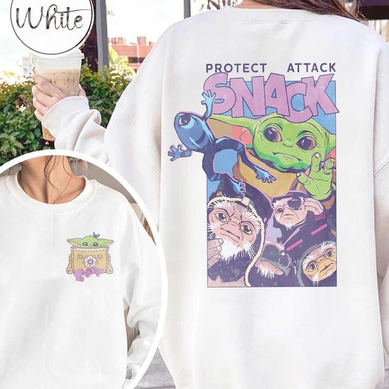 May include: White sweatshirt featuring a colorful graphic of a green alien character with the text "PROTECT ATTACK SNACK" on the back. A smaller graphic of the alien is on the front.