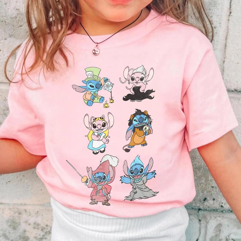 Puede incluir: Una camiseta de manga corta de color rosa claro con un estampado gr&aacute;fico de seis personajes de dibujos animados. Los personajes aparecen con diversos disfraces, como un anfitri&oacute;n de una fiesta de t&eacute;, un personaje rubio, un espadach&iacute;n y un fantasma.