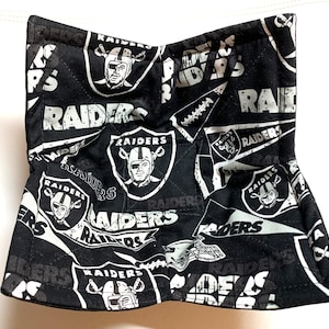 May include: Black and white fabric bowl with a repeated pattern of the Las Vegas Raiders logo and the word "RAIDERS".