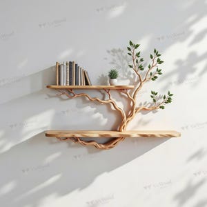 Könnte beinhalten: Ein hölzernes Wandregal in Form eines Baumes mit zwei Regalböden. Die hellen Holzregale werden von einem Baumstamm und Ästen getragen. Bücher und eine kleine Topfpflanze befinden sich auf dem oberen Regal. Grüne Blätter schmücken die Äste.