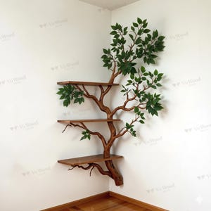 May include: A wooden corner shelf designed to resemble a tree, with three rectangular shelves and faux green leaves. The tree trunk and branches are a warm brown color, creating a natural aesthetic. The shelves are made of wood.