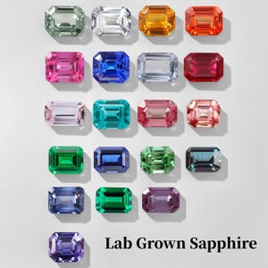 Puede incluir: Una colección de zafiros cultivados en laboratorio en varios colores, incluyendo verde, azul, rosa y naranja. Cada gema tiene un corte esmeralda y se muestra sobre un fondo blanco. El texto "Lab Grown Sapphire" está en la parte inferior.