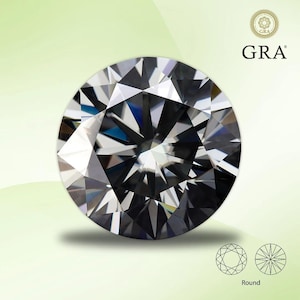 Peut inclure: Une pierre précieuse ronde, claire et facetée avec une teinte grise. La pierre précieuse est placée sur un fond vert avec le mot "GRA" en texte blanc.