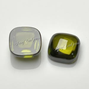 May include: Two square-shaped, olive green gemstones with rounded corners and a smooth, polished surface. Each stone features a faceted top and a translucent appearance. The text FengYunGems is overlaid across both stones in a cursive font.