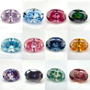 May include: A collection of twelve oval-cut gemstones displayed in a grid, featuring a variety of vibrant colours including lavender, bright blue, hot pink, deep green, light blue, soft pink, dark blue, golden yellow, purple, black, mint, and maroon.