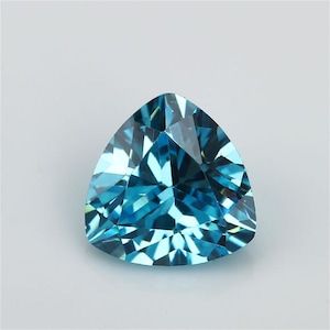 May include: A loose, trillion-cut gemstone with a vibrant, translucent blue colour. The stone features a complex arrangement of triangular and trapezoidal facets that create a high degree of light reflection and internal brilliance throughout the surface.