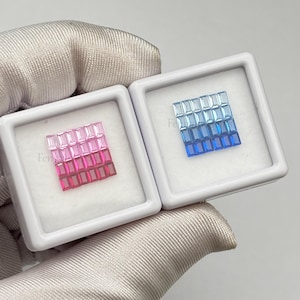 Può includere: Due vetrine bianche contengono ciascuna una collezione di gemme rettangolari. Una vetrina presenta un gradiente di pietre da rosa a rosse, mentre l'altra mostra un gradiente blu. Le gemme sono disposte a griglia.