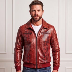 May include: A red snakeskin-patterned leather jacket with a pointed collar, a central black zip, two zipped chest pockets, and two lower zipped pockets. The jacket features ribbed cuffs and a ribbed hem, worn over a plain white t-shirt.