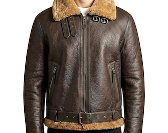 Può includere: Una giacca in pelle marrone scuro con un colletto e una fodera interna in montone color cuoio spesso. La giacca presenta una cerniera centrale, due tasche verticali con cerniera, una cintura con fibbia e due cinturini regolabili sul colletto.