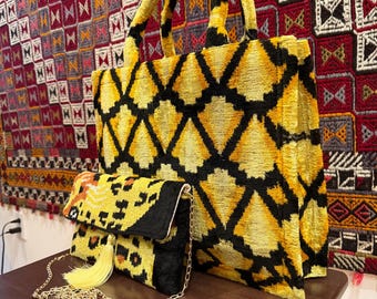May include: A yellow and black patterned tote bag and matching clutch with a gold chain. The tote bag has a geometric design, and the clutch has a leopard print. Both bags are made of a soft, textured material.