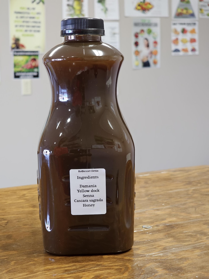 May include: A brown glass bottle with a black cap, labeled "Bathroom Detox" and listing ingredients: Damiana, Yellow dock, Senna, Cascara sagrada, Honey.