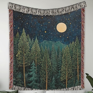 May include: A woven tapestry wall hanging with a dark blue background featuring a full moon and a forest of green trees under a starry night sky.