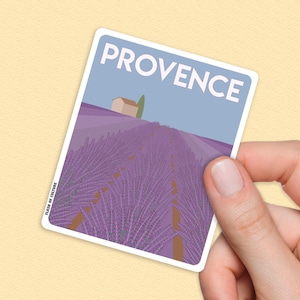 Peut inclure: Un autocollant représentant un champ de lavande violet avec une petite maison au loin. Le texte "PROVENCE" est imprimé en blanc en haut de l'autocollant.