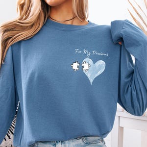 Puede incluir: Una camisa azul de manga larga con el texto "For My Precious" y un corazón azul con dos piezas de rompecabezas dentro.