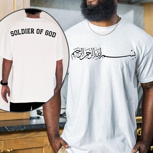 May include: White t-shirt with black Arabic calligraphy on the front and the words "SOLDIER OF GOD" printed on the back. The shirt is made of a soft material and has short sleeves.