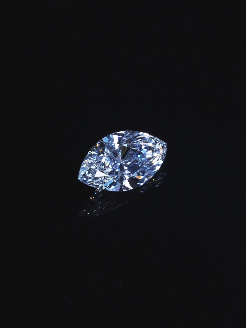 May include: A large, pear-shaped, light blue diamond with many facets. The gemstone is set against a black background, creating a striking contrast. The diamond's surface reflects light, showcasing its brilliance and clarity. This image highlights the beauty of a precious gemstone.