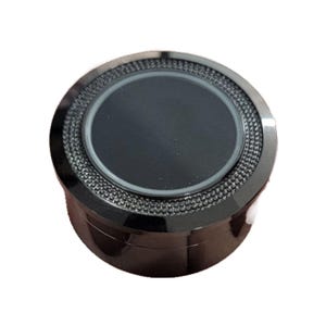 May include: A black, round object with a textured, mesh-like band around the top. The center is a smooth, dark circle. The object has a shiny, metallic appearance.