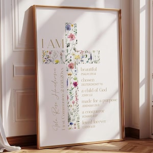 May include: Framed art print featuring a cross shape adorned with colorful floral illustrations. The words "I AM" are at the top, with additional text including "beautiful," "chosen," and Bible verses. The print is in a gold frame.