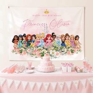 Puede incluir: Una escena de fiesta de cumpleaños rosa con una pancarta con ilustraciones de princesas y el texto "Happy 2nd Birthday Princess Olivia". Una tarta de tres pisos, cupcakes y bebidas rosas están sobre la mesa, decorada con un mantel rosa y una pancarta.