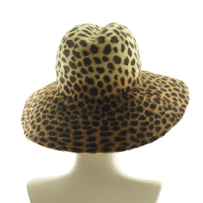 May include: A wide-brimmed hat with a leopard print pattern. The hat is made of a soft, furry material and has a wide, floppy brim.