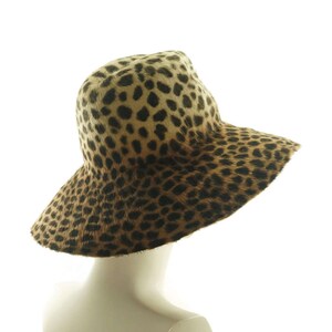 May include: A wide-brimmed hat with a leopard print pattern. The hat is made of a soft, furry material and has a brown and tan color scheme.