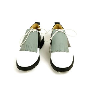May include: A pair of white and black golf shoes with grey fringe accents and white laces.