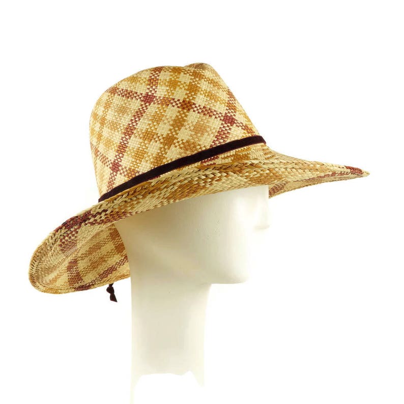 May include: A brown and tan straw cowboy hat with a brown ribbon band. The hat is on a white mannequin head.