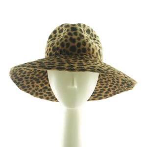May include: A wide-brimmed hat with a leopard print pattern. The hat is made of a soft, furry material and has a wide, floppy brim.