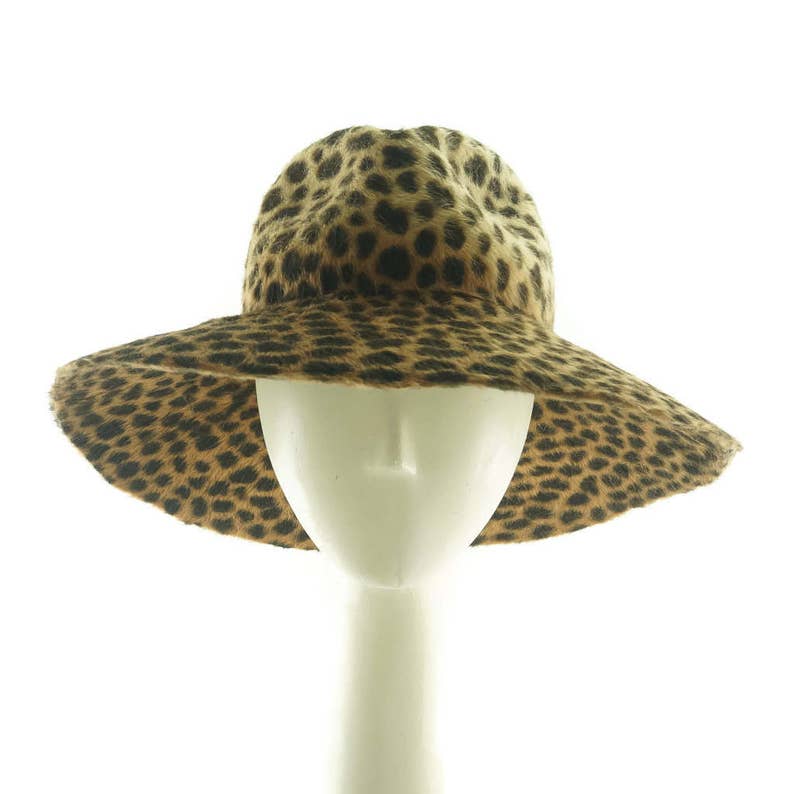 May include: A wide-brimmed hat with a leopard print pattern. The hat is made of a soft, furry material and has a wide, floppy brim.