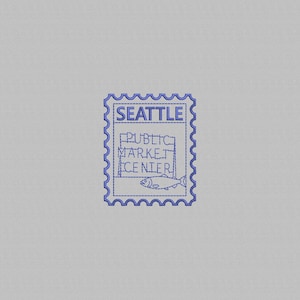 Pode incluir: Um design de selo postal bordado em azul sobre um fundo de tecido cinza claro. O design apresenta o texto SEATTLE e PUBLIC MARKET CENTER, juntamente com um gráfico de um peixe, tudo renderizado num estilo de contorno costurado simples.