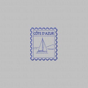 Op de afbeelding: Een blauw geborduurd postzegelontwerp op een lichtgrijze stoffen achtergrond. Het ontwerp toont een zeilboot op het water met bergen op de achtergrond en de tekst CÔTE D'AZUR in blauwe hoofdletters aan de bovenzijde van het ontwerp.