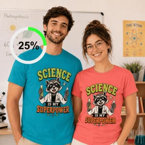 May include: A bright blue t-shirt and a coral pink t-shirt, each featuring a graphic of a raccoon wearing glasses and a lab coat, holding test tubes. The text reads "SCIENCE IS MY SUPERPOWER" in bold, stylised lettering above and below the raccoon.