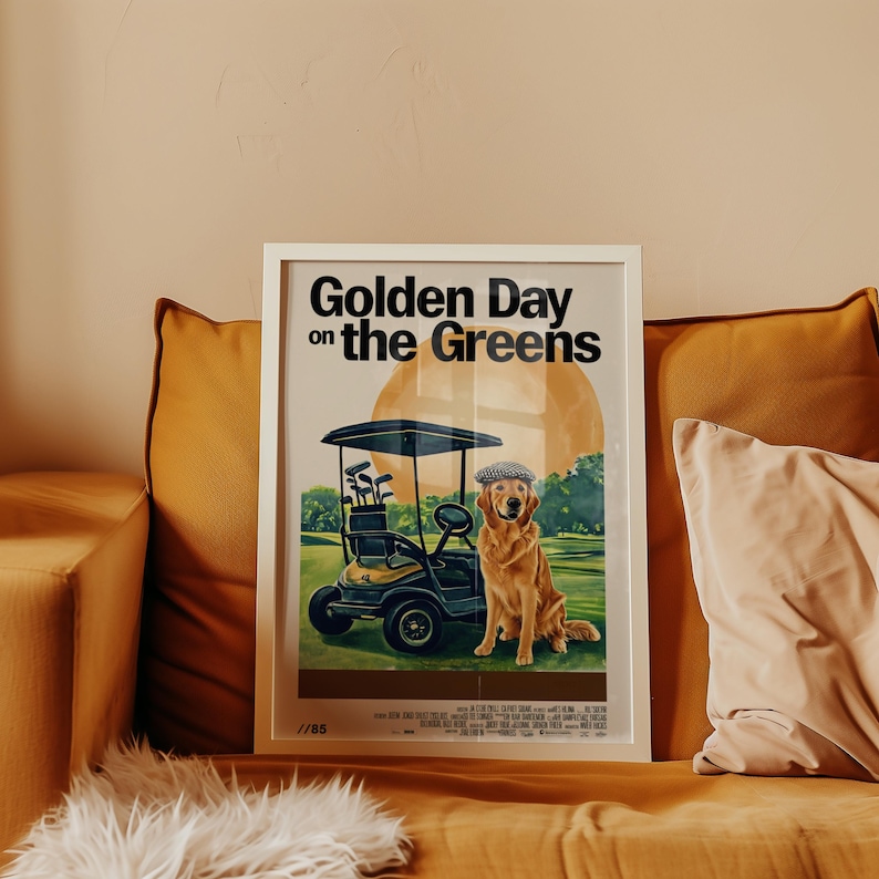 May include: A white framed poster with the text "Golden Day on the Greens" in black. The poster features a cartoon illustration of a golden retriever wearing a cap and riding in a golf cart on a green golf course.