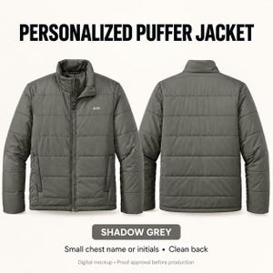 May include: A shadow grey puffer jacket featuring a full-length front zipper, a high collar, and long sleeves. The front chest area displays the name ALEX in white text. The back of the jacket is plain with horizontal quilted stitching throughout.