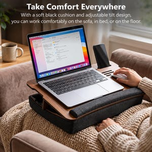 Puede incluir: Un escritorio de madera para portátil con superficie inclinable ajustable, que cuenta con una base de cojín negro suave, una ranura para smartphone y un reposamuñecas. El escritorio sostiene un portátil plateado y un ratón blanco.