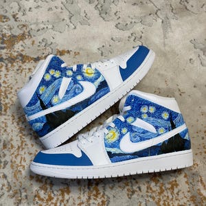 May include: Pair of white and blue sneakers with a custom design inspired by Van Gogh's "Starry Night" painting. The shoes feature a blue and white color scheme, with the iconic artwork covering the sides and heel.