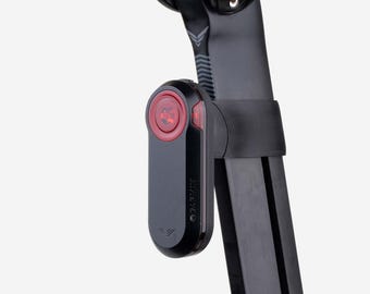 May include: A black Garmin bicycle radar tail light mounted to a black seat post. The device features a vertical rectangular shape with rounded edges, a circular red lens at the top, and the Garmin brand name printed vertically on the side casing.