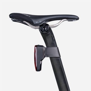 May include: A black bicycle seat with the text "SLR" and a silver metal support. A black seat post with a red taillight is attached. The taillight is mounted with a black strap.