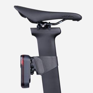 Puede incluir: Asiento de bicicleta negro con la marca "Cervelo" impresa. Una tija de sillín negra está unida al asiento. Una luz trasera Garmin negra está unida a la tija del sillín.