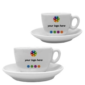 Könnte beinhalten: Zwei weiße Espressotassen und Untertassen aus Keramik. Jede Tasse hat ein farbenfrohes Logo und den Text "your logo here" auf der Vorderseite. Darunter befinden sich vier farbige Sternchen. Die Tassen haben einen Henkel und stehen auf einer weißen Untertasse.