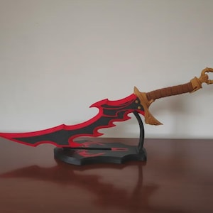May include: A fantasy-style sword featuring a sharp, curved blade with a black and red color scheme. The hilt is brown with a gold-colored crossguard and a decorative pommel. The sword is mounted on a black display stand with red accents.