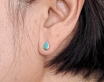 Puede incluir: Un par de pendientes de plata en forma de lágrima con piedras turquesa.